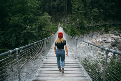 Étudiante marchant sur un pont en pleine nature, image de développement personnel lié au système scolaire canadien.